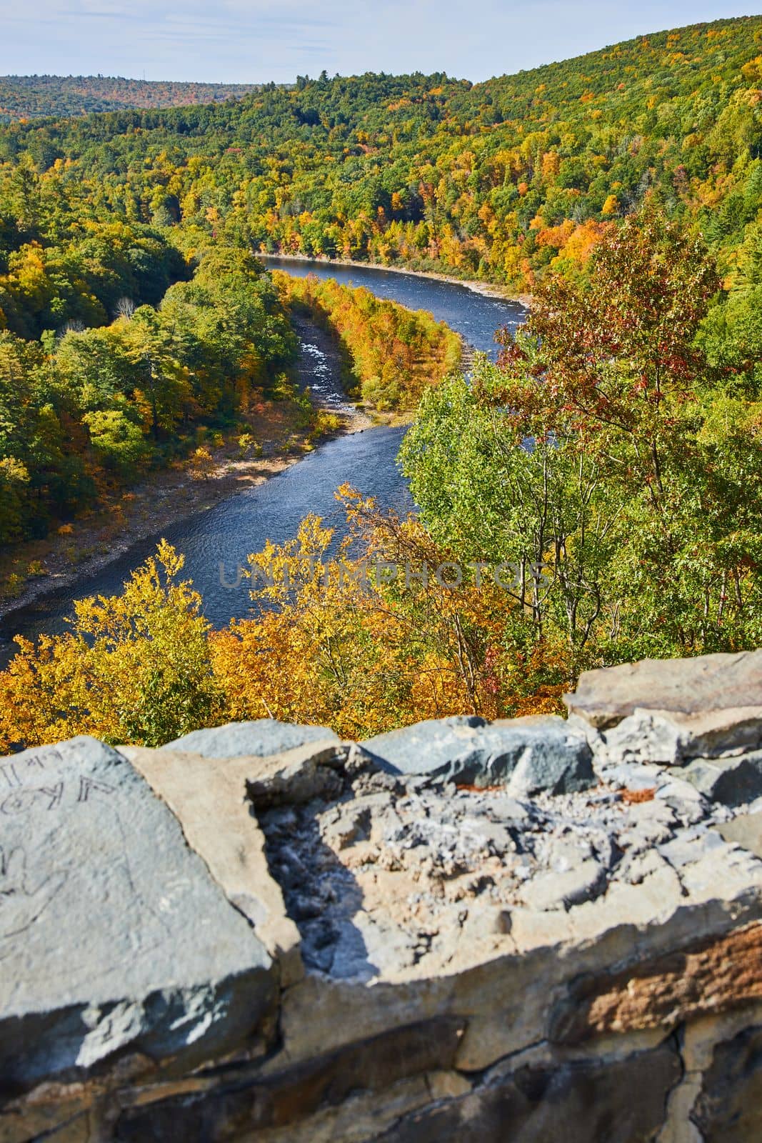 Image of Damaged stone wall overlooking Delaware River winding through early fall forest