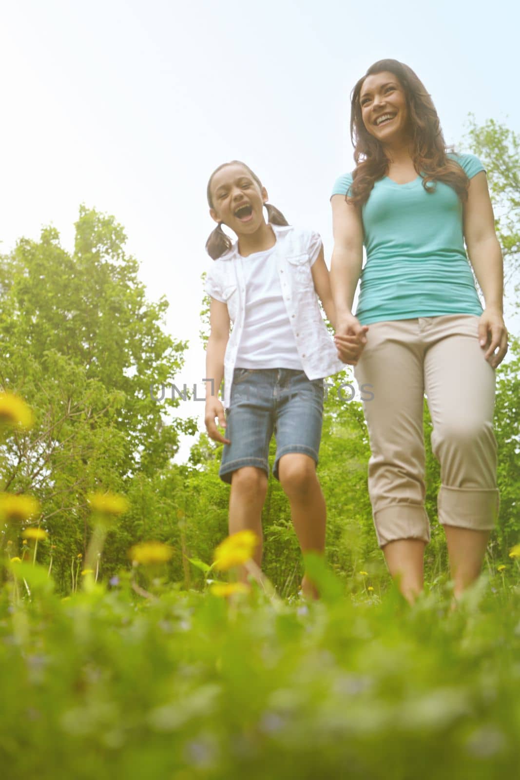 What a beautiful day. A mother and daughter holding hands while walking in the outdoors. by YuriArcurs