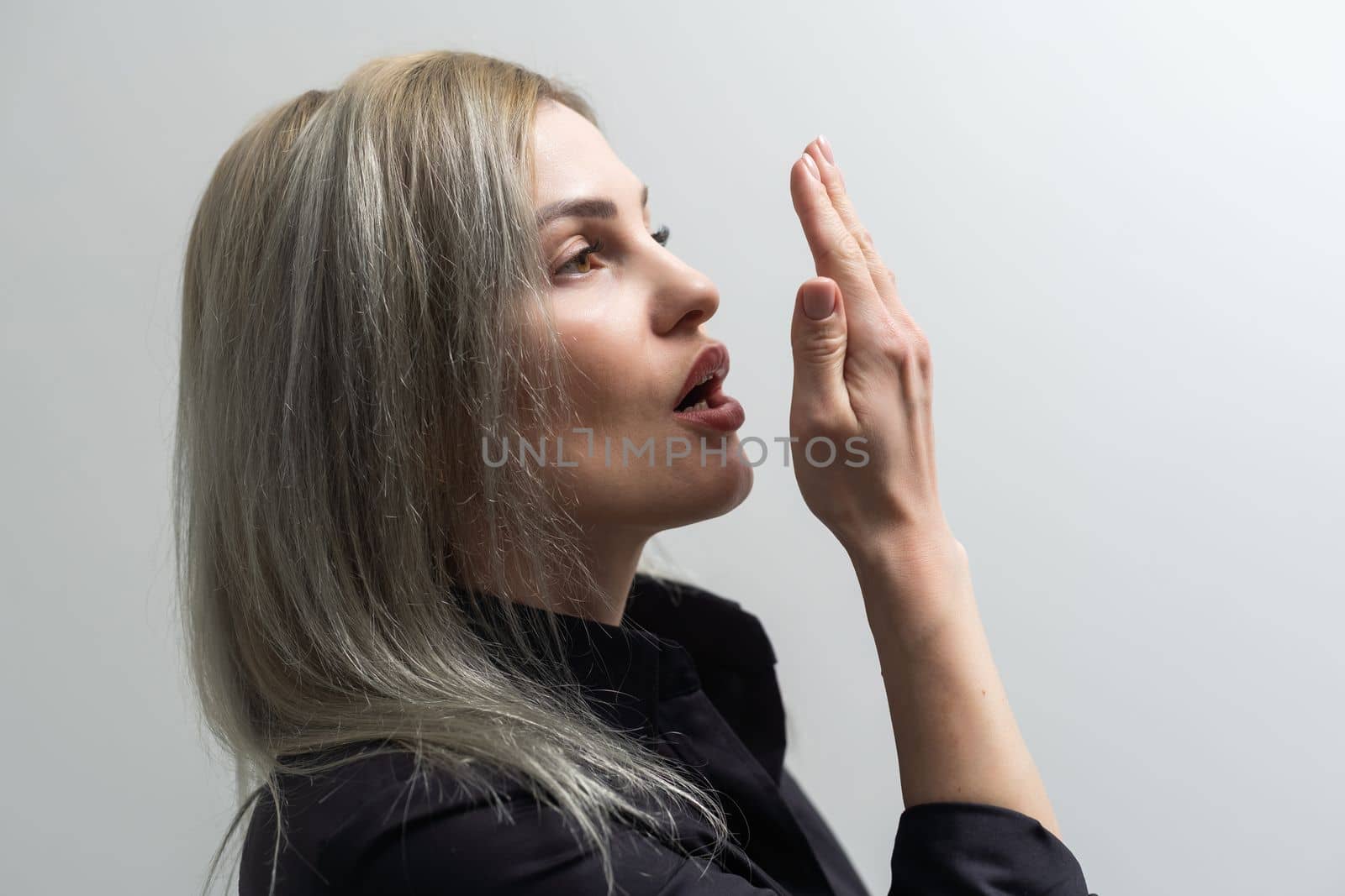 young woman checking her breath with her hand.