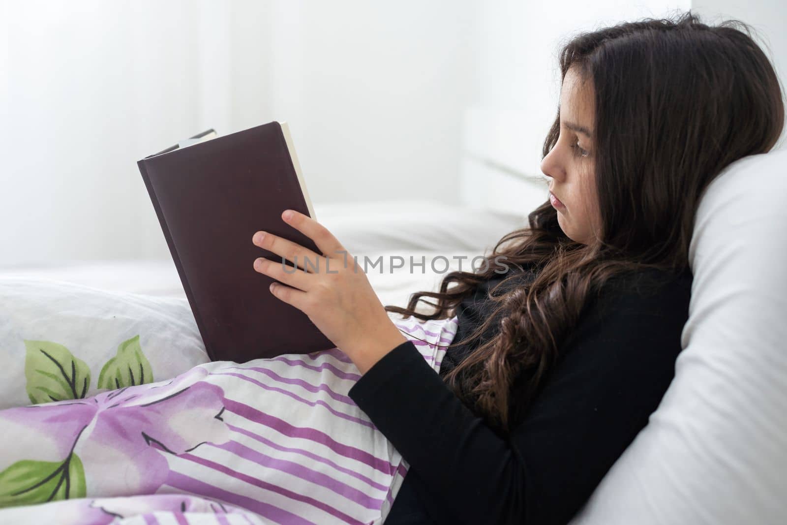 teenage girl with a book in bed.