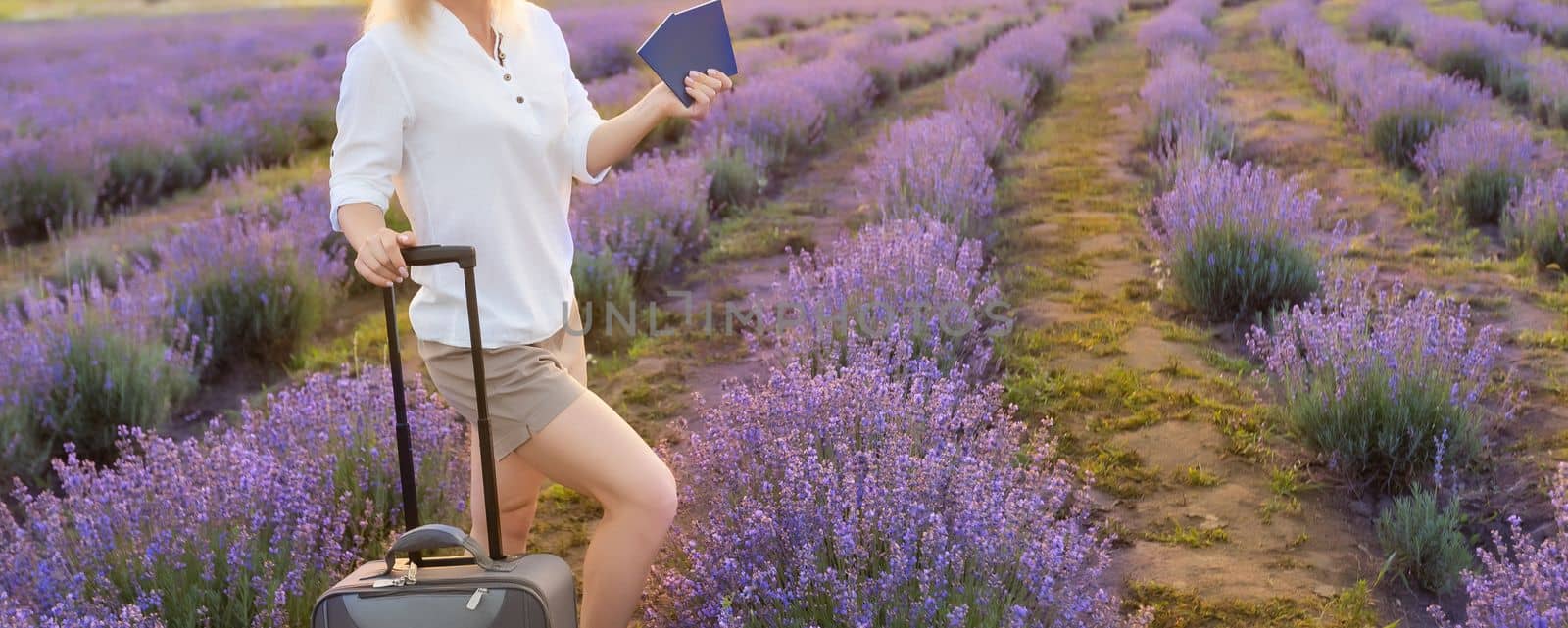 woman with suitcase and passport in lavender field.