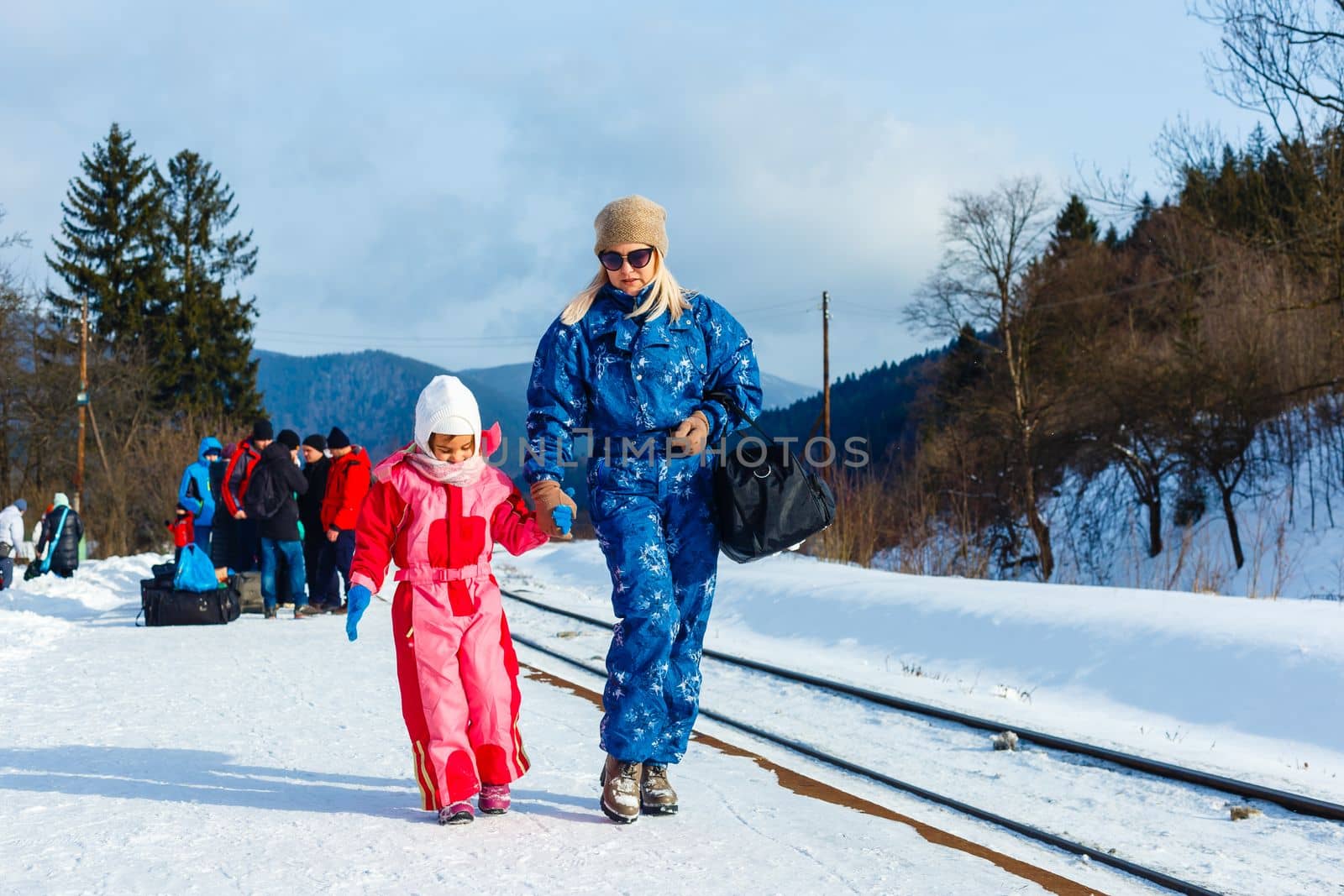 A woman waits with her daughter after heavy snowfall for her train to arrive