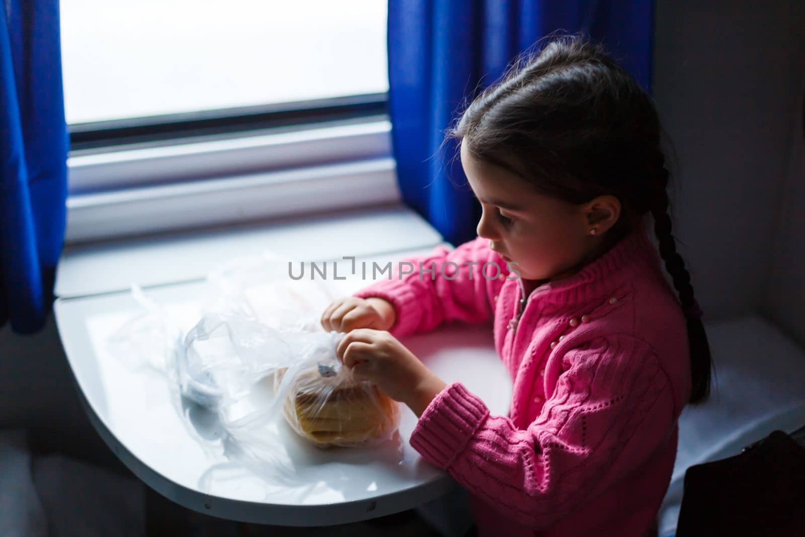 Sad little girl traveling on train. Child in winter clothes travels by rail.