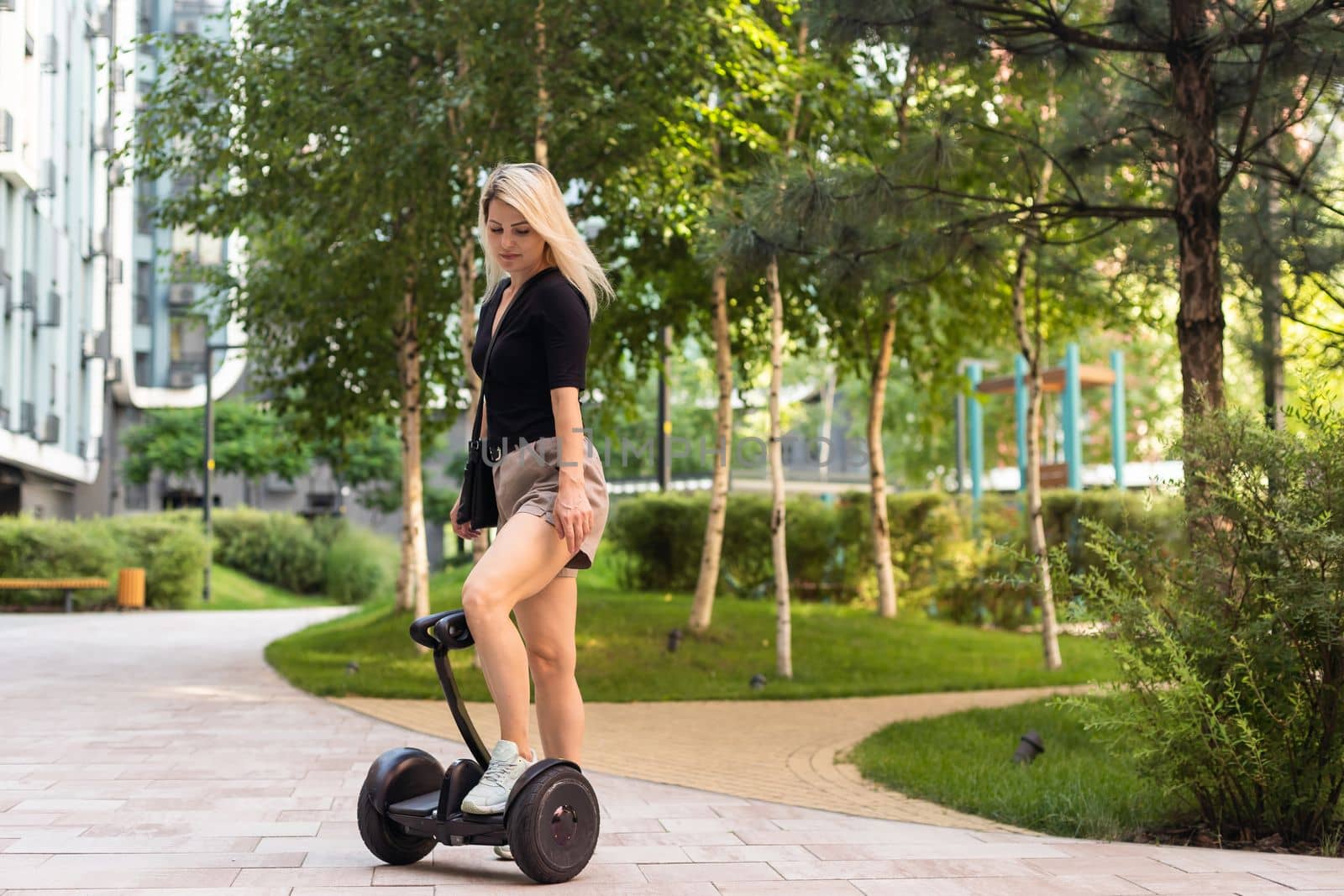 woman riding electric mini segway hover board scooter in green park. Good summer weather, ecological urban transportation technology and pretty model. Electric self-balancing scooter board by Andelov13