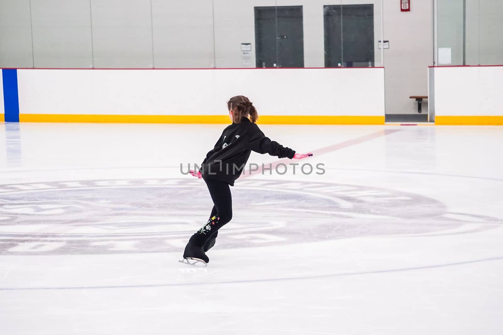 Little girl practicing figure skating at the indoor ice rink.