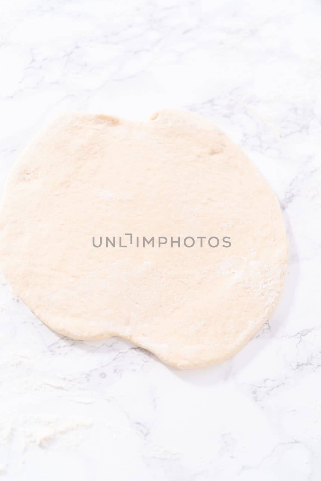 Rolling pizza dough with a french rolling pin to prepare cinnamon dessert pizza.