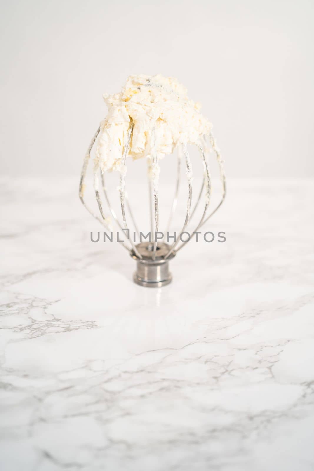 Eggnog buttercream frosting on a whisk from an electric kitchen mixer.