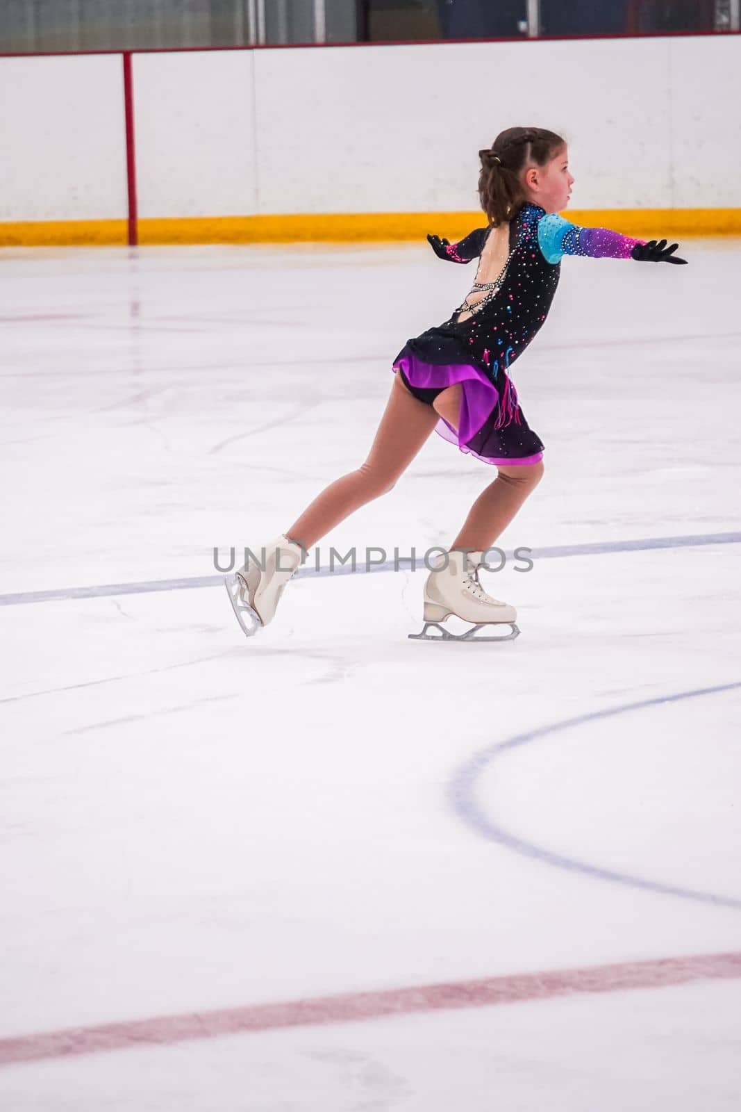 Little girl practicing before her figure skating competition at the indoor ice rink.