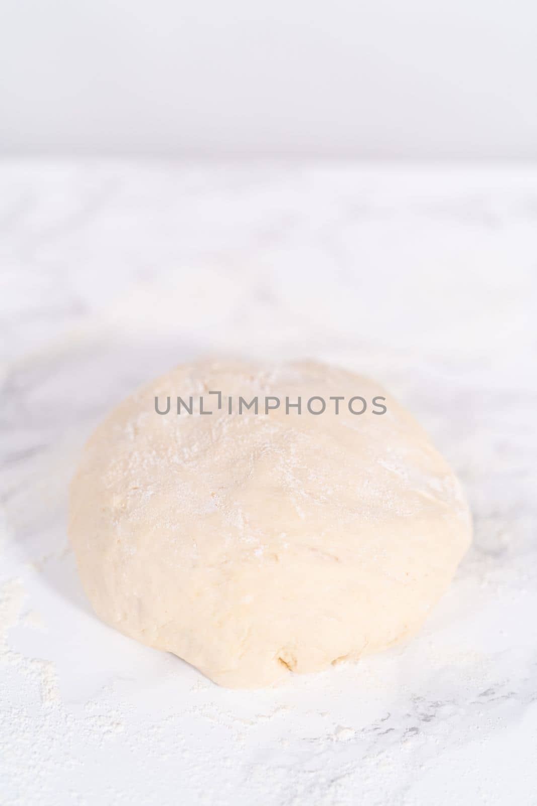 Rolling pizza dough with a french rolling pin to prepare cinnamon dessert pizza.