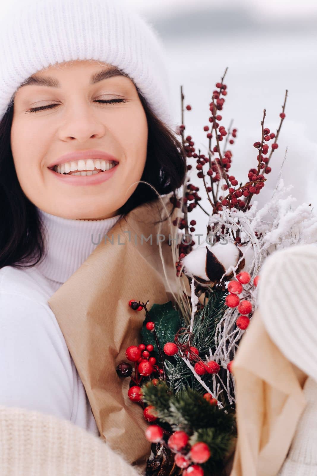 A girl in a beige cardigan and winter flowers walks in nature in the snowy season. Winter weather by Lobachad