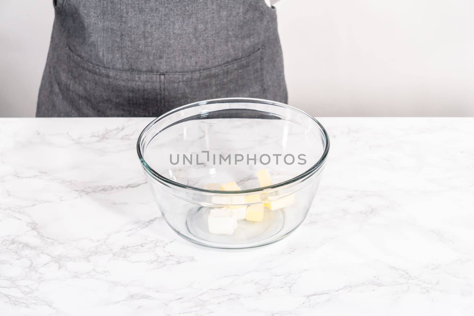 Mixing ingredients in a large glass mixing bowl to prepare cream cheese drizzle sauce.