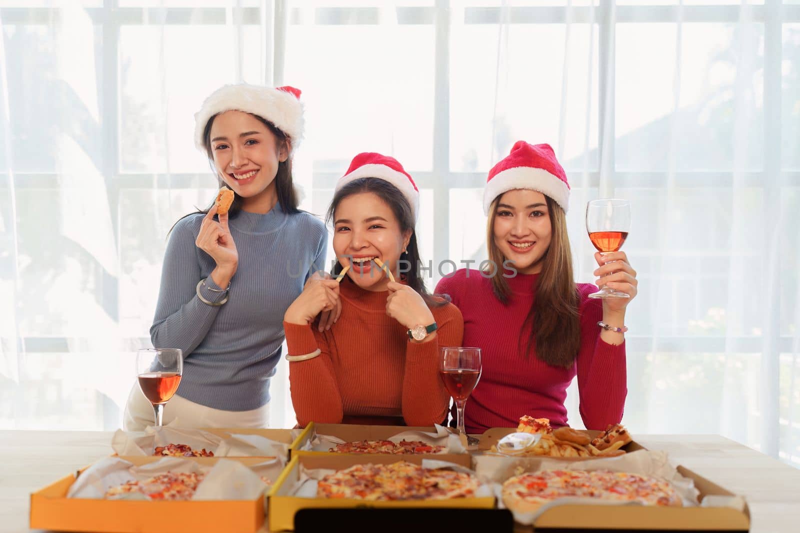 Friends at birthday party clinking glasses with champagne and pizza, enjoying Christmas vacation, pizza on the table. Holiday Party event.