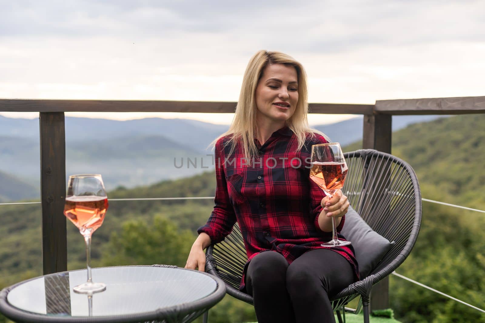 Young woman with glass of wine in peaceful mountains by Andelov13