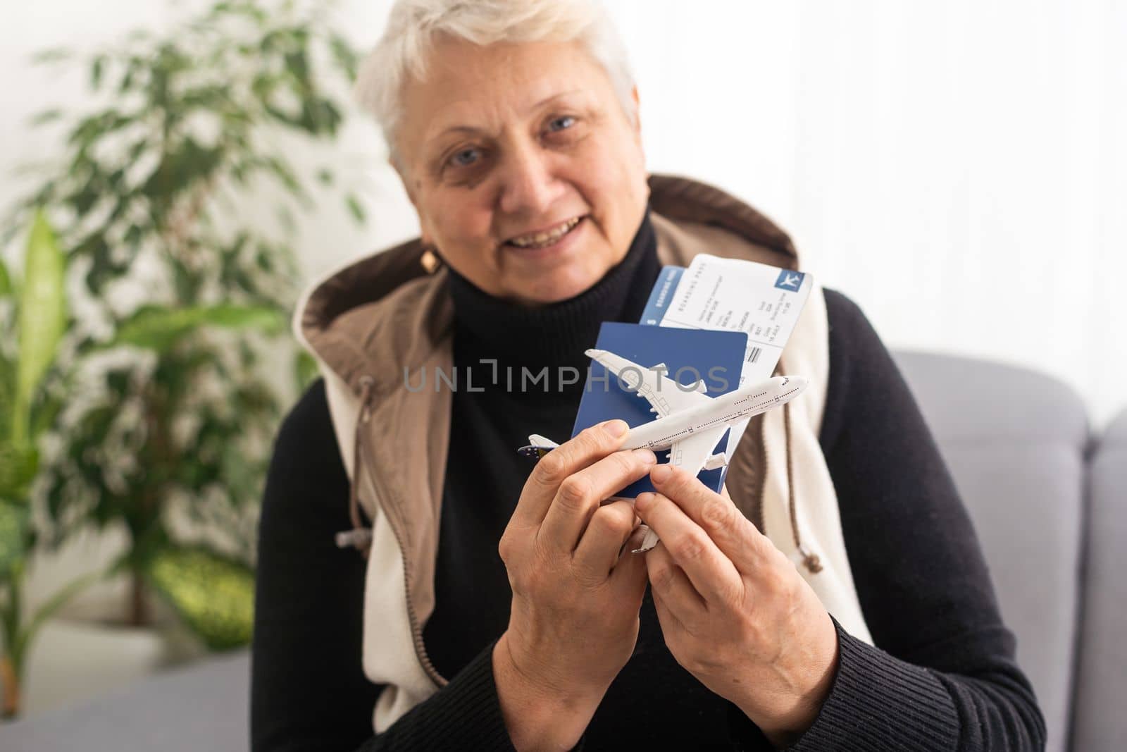 old woman holding Passport, boarding pass and toy airplane by Andelov13