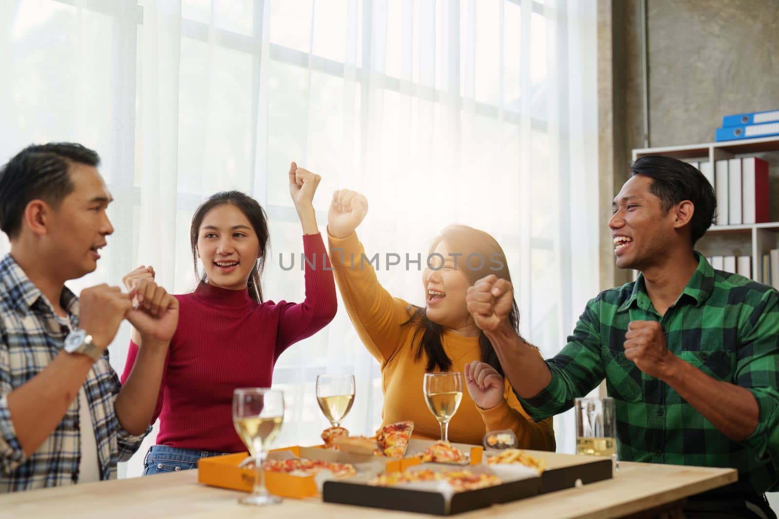 Friends at birthday party clinking glasses with champagne and pizza, enjoying Christmas vacation, pizza on the table. Holiday Party event