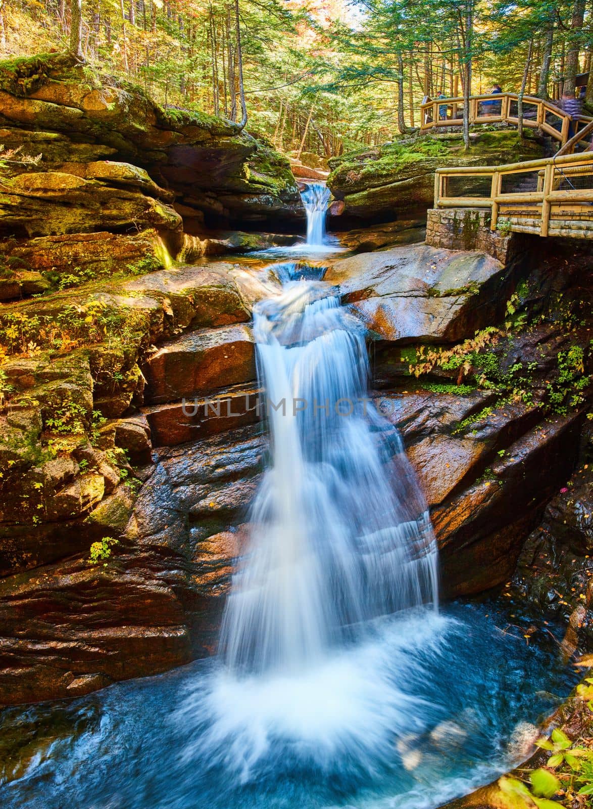 Image of Stunning wide view of New Hampshire waterfalls tucked into lush fall forest and boardwalk overlooks for tourists
