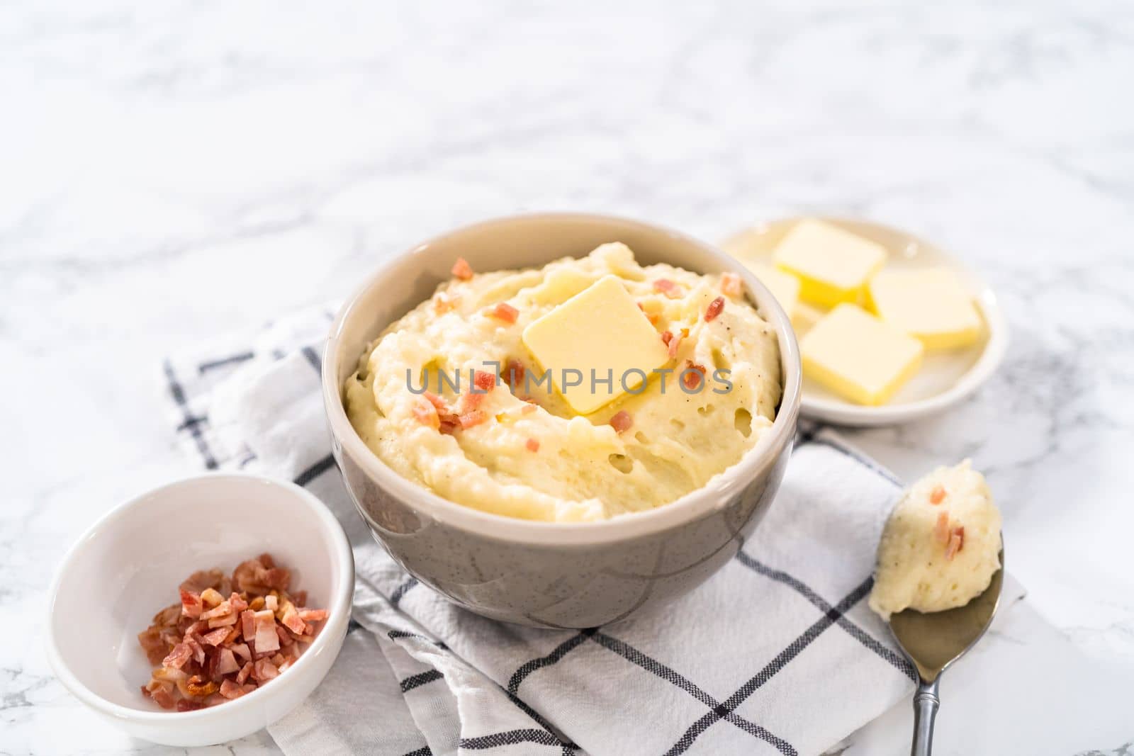Mashed potatoes. Creamy mashed potatoes garnished with a slice of butter and bacon bits in a bowl.