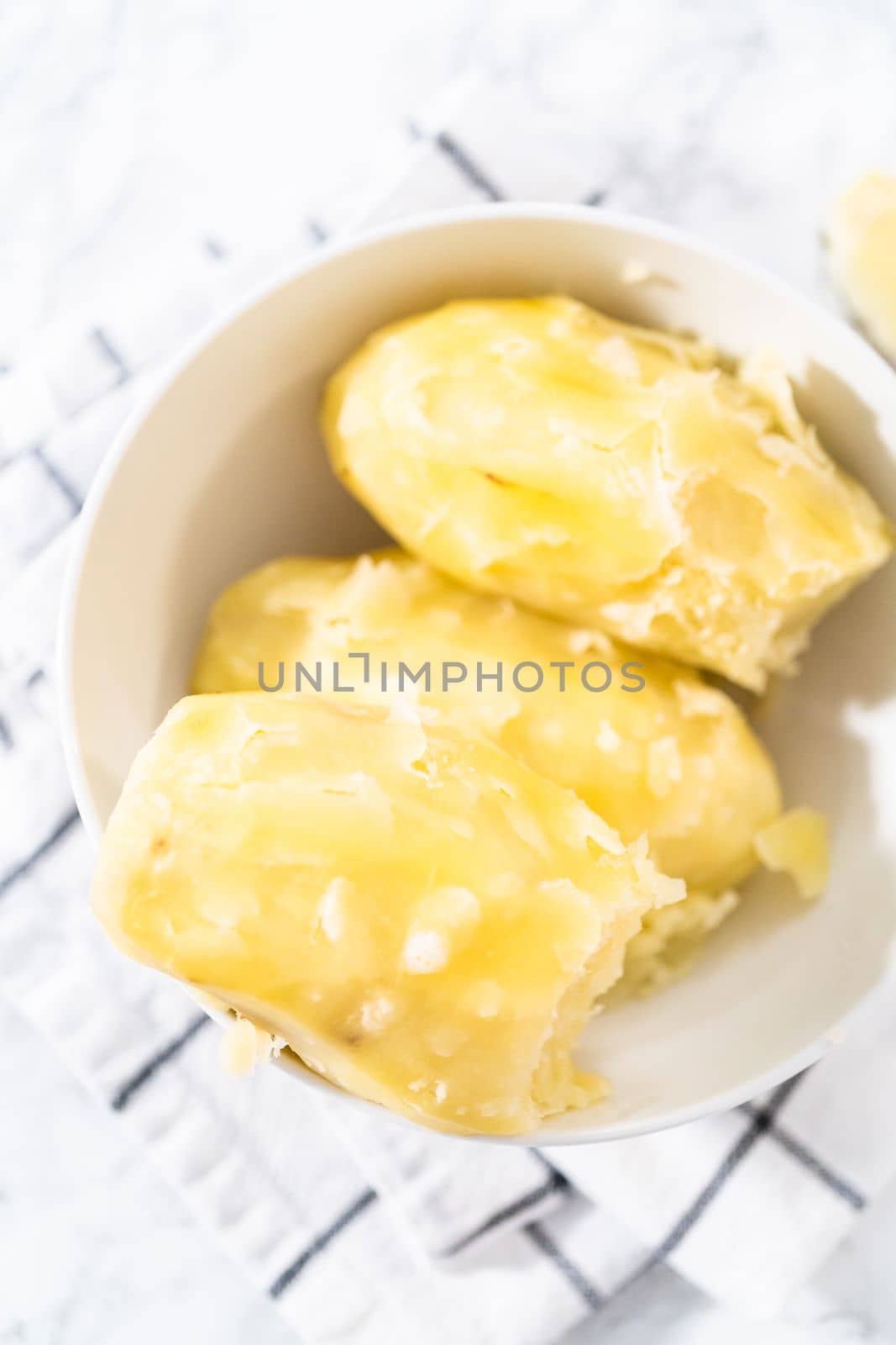 Mashed potatoes. Cooking whole peeled potatoes in a white bowl.
