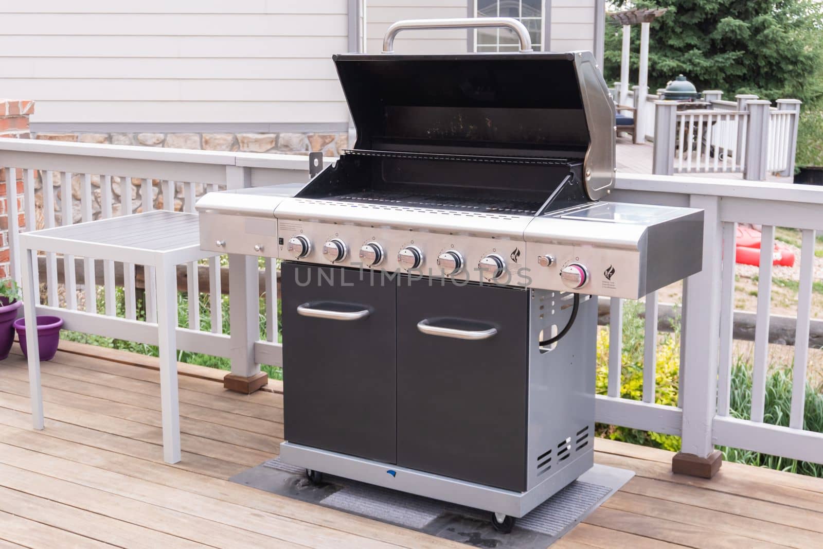 Outdoor six-burner gas grill on the back patio of a luxury single-family home.