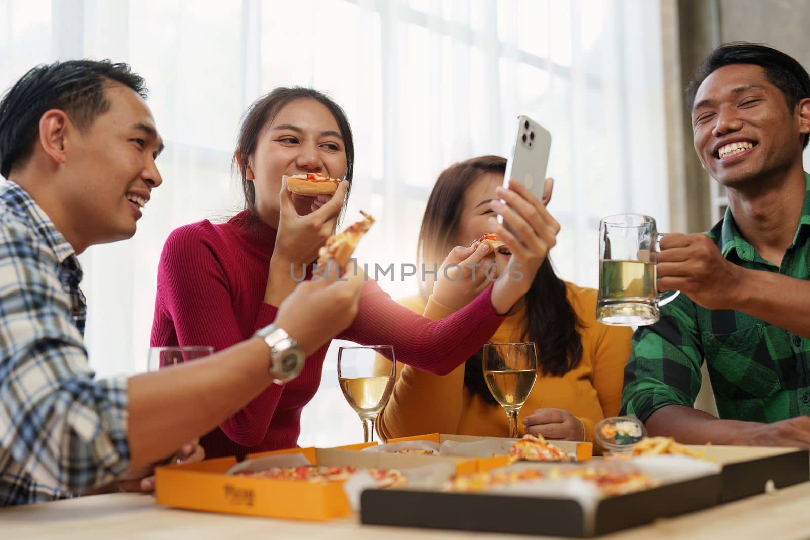 Friends at birthday party clinking glasses with champagne and pizza, enjoying Christmas vacation, pizza on the table. Holiday Party event