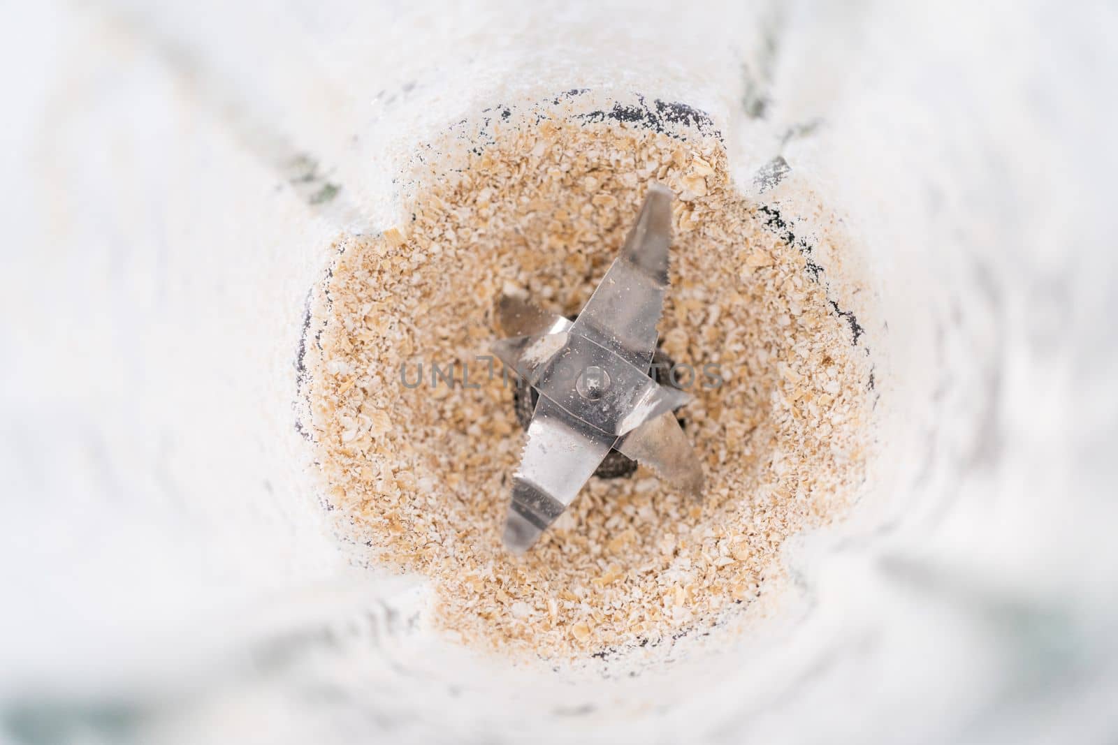 Blending ingredients for healthy breakfast strawberry banana smoothie in a kitchen blender.