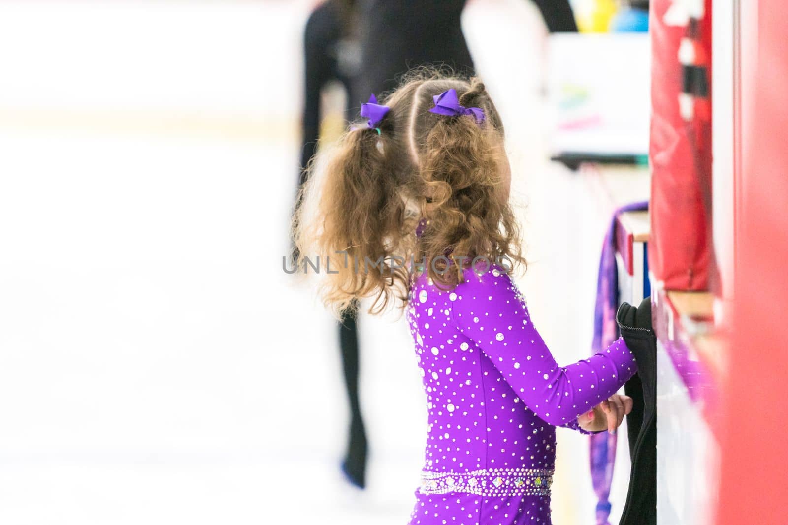 Little girl practicing figure skating on an indoor ice skating rink.