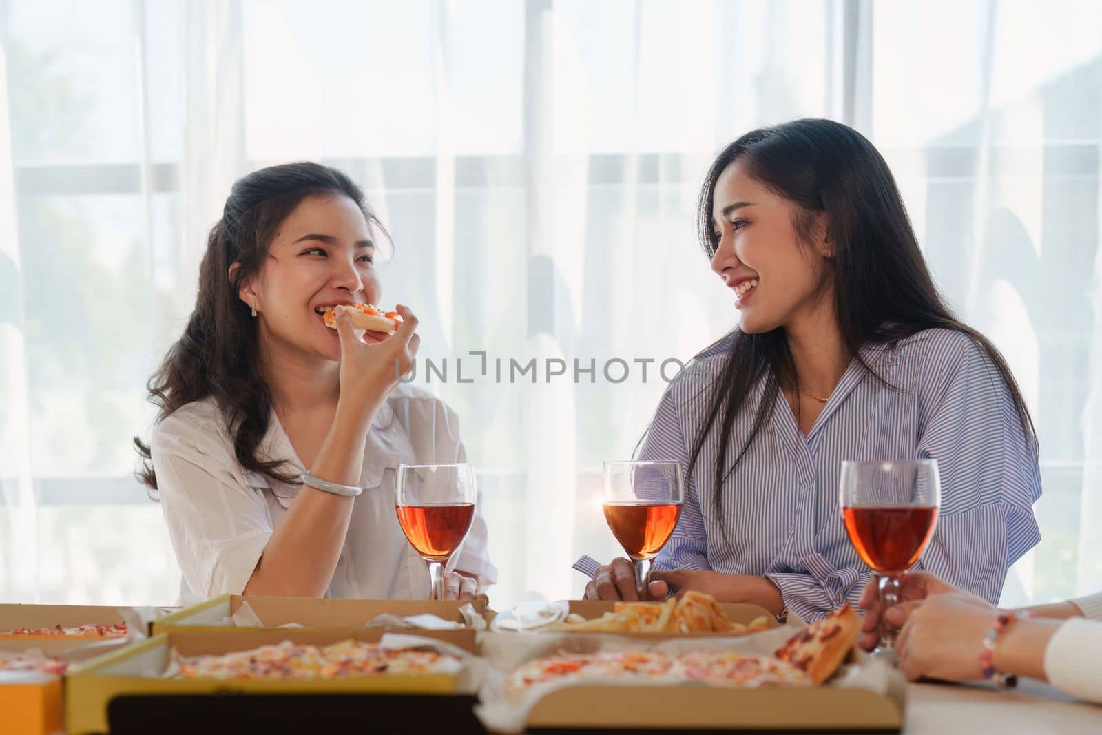 Friends at birthday party clinking glasses with champagne and pizza, enjoying Christmas vacation, pizza on the table. Holiday Party event.