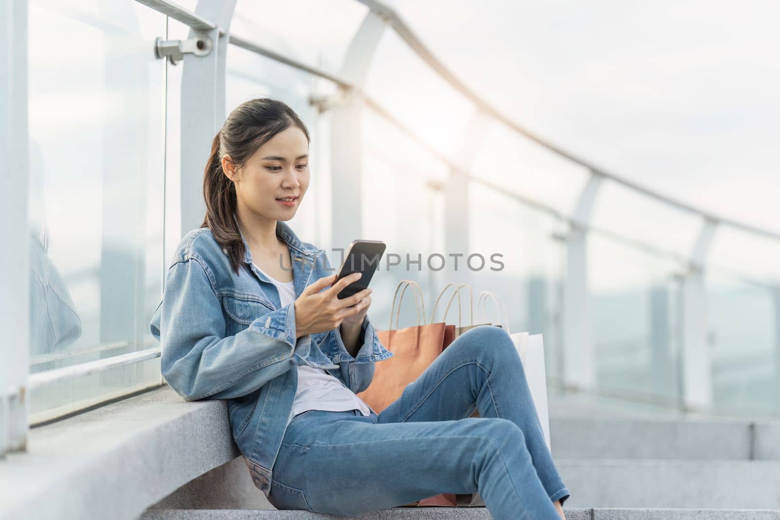 Asian fashionable woman walking at shopping mall with shopping bags while flash sale promotion.