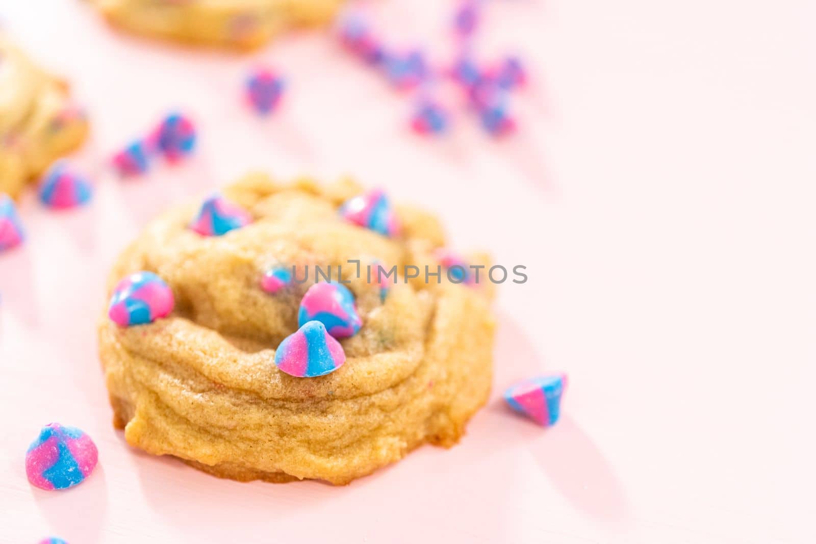 Freshly baked unicorn chocolate chip cookies with rainbow chocolate chips on the counter.