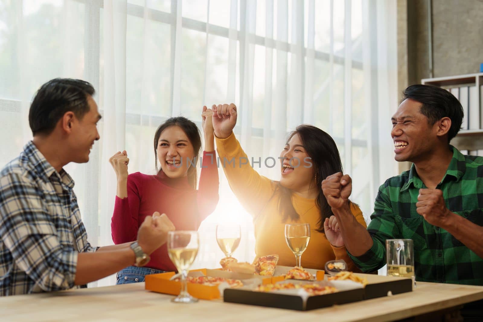 Friends at birthday party clinking glasses with champagne and pizza, enjoying Christmas vacation, pizza on the table. Holiday Party event