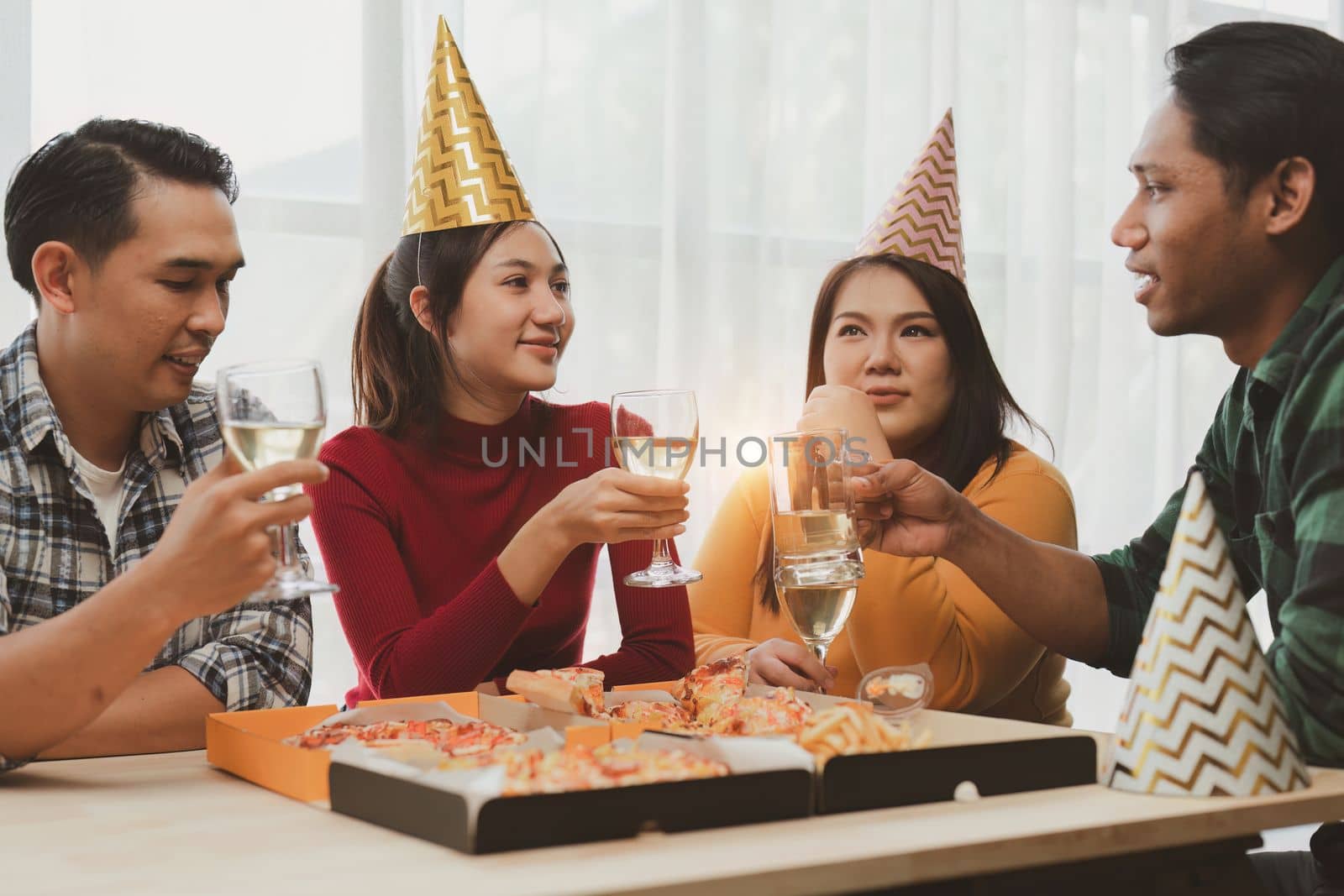 Friends at birthday party clinking glasses with champagne and pizza, enjoying Christmas vacation, pizza on the table. Holiday Party event