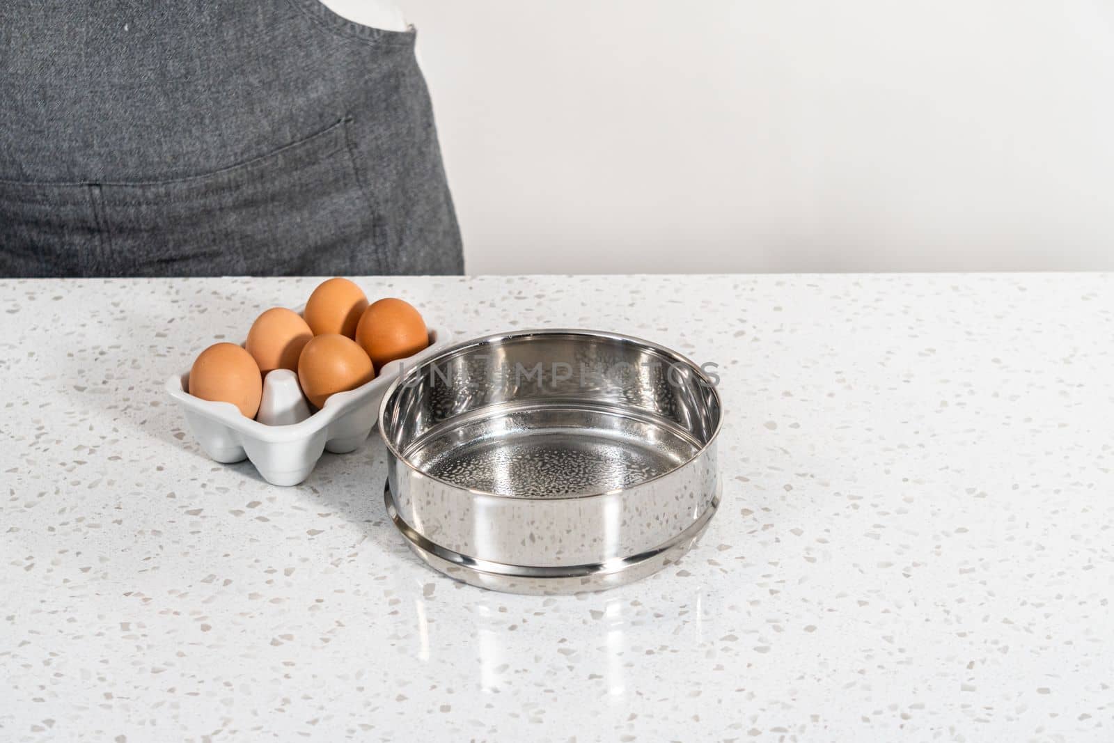 Filling metal pressure cooker insert with raw eggs to cook boiled eggs for potato salad.