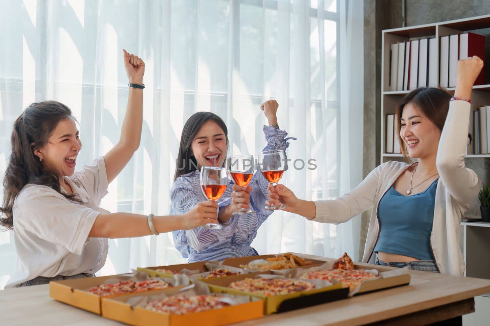 Friends at birthday party clinking glasses with champagne and pizza, enjoying Christmas vacation, pizza on the table. Holiday Party event.
