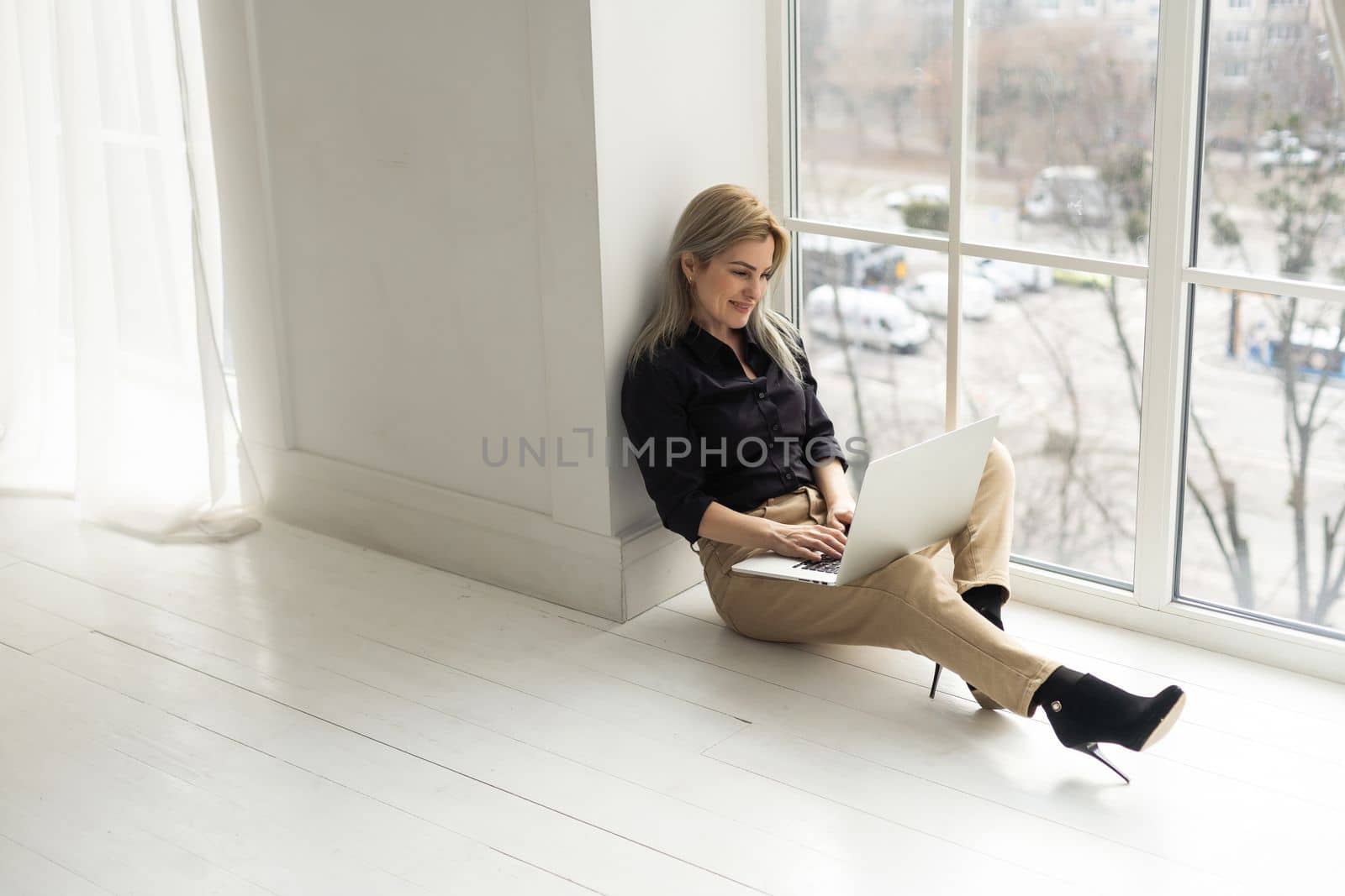 Image of young pleased happy cheerful cute beautiful business woman indoors in office using laptop computer.