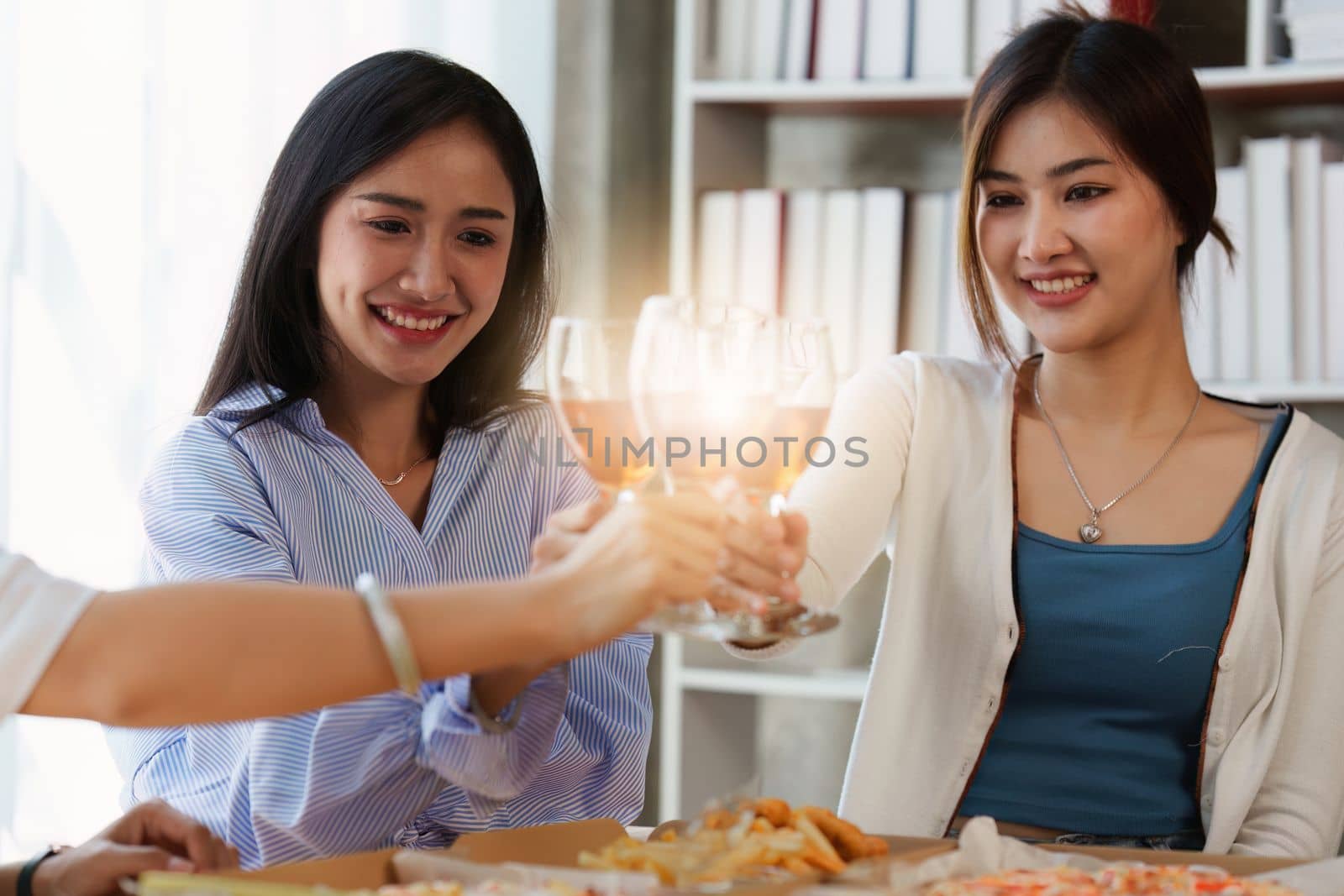 Friends at birthday party clinking glasses with champagne and pizza, enjoying Christmas vacation, pizza on the table. Holiday Party event.