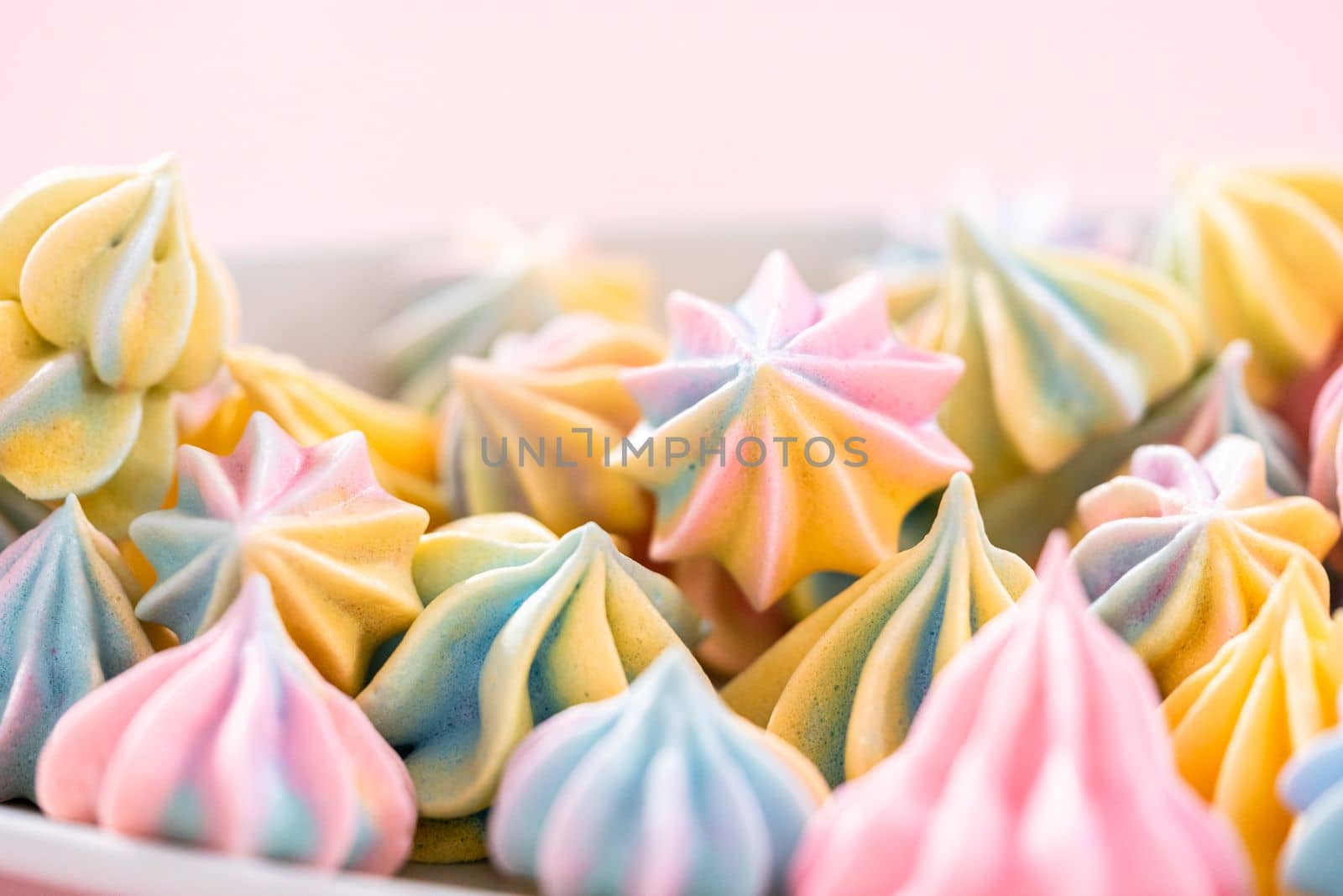 Multicolored unicorn meringue cookies on a white serving plate.