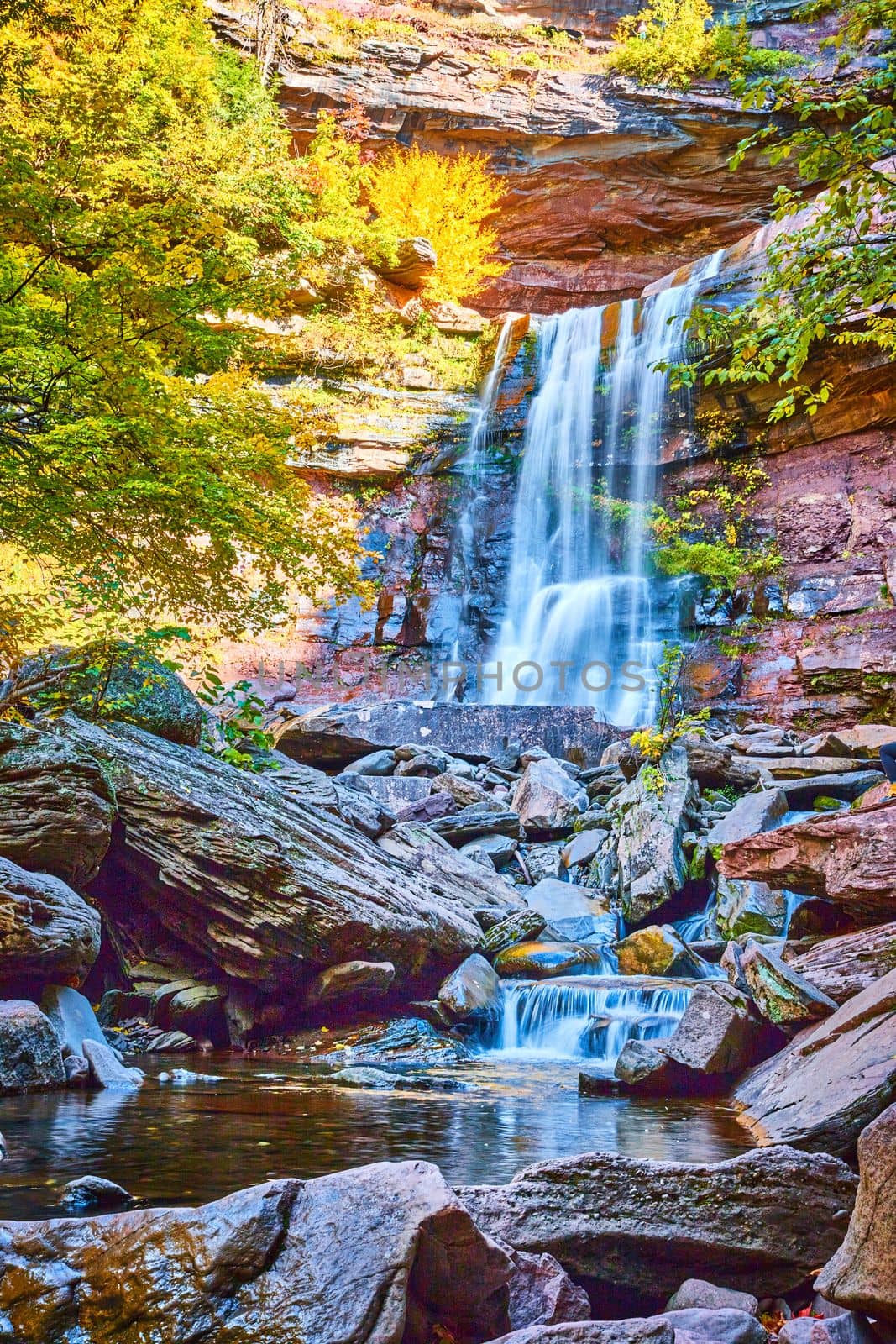 Image of Looking up towards layers of cascading waterfalls over rocky cliffs during fall in golden light of New York