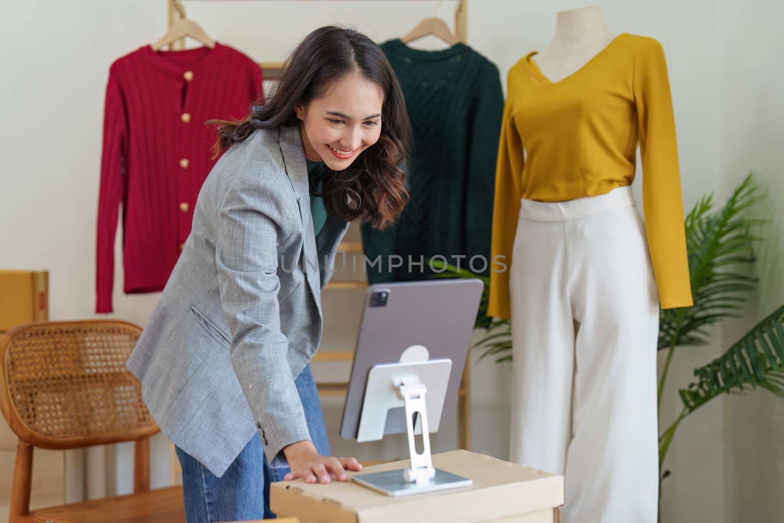 Asian Woman fashion designer cloth tailor creative working for new collection. Happy online store owner preparing an order for shipping.
