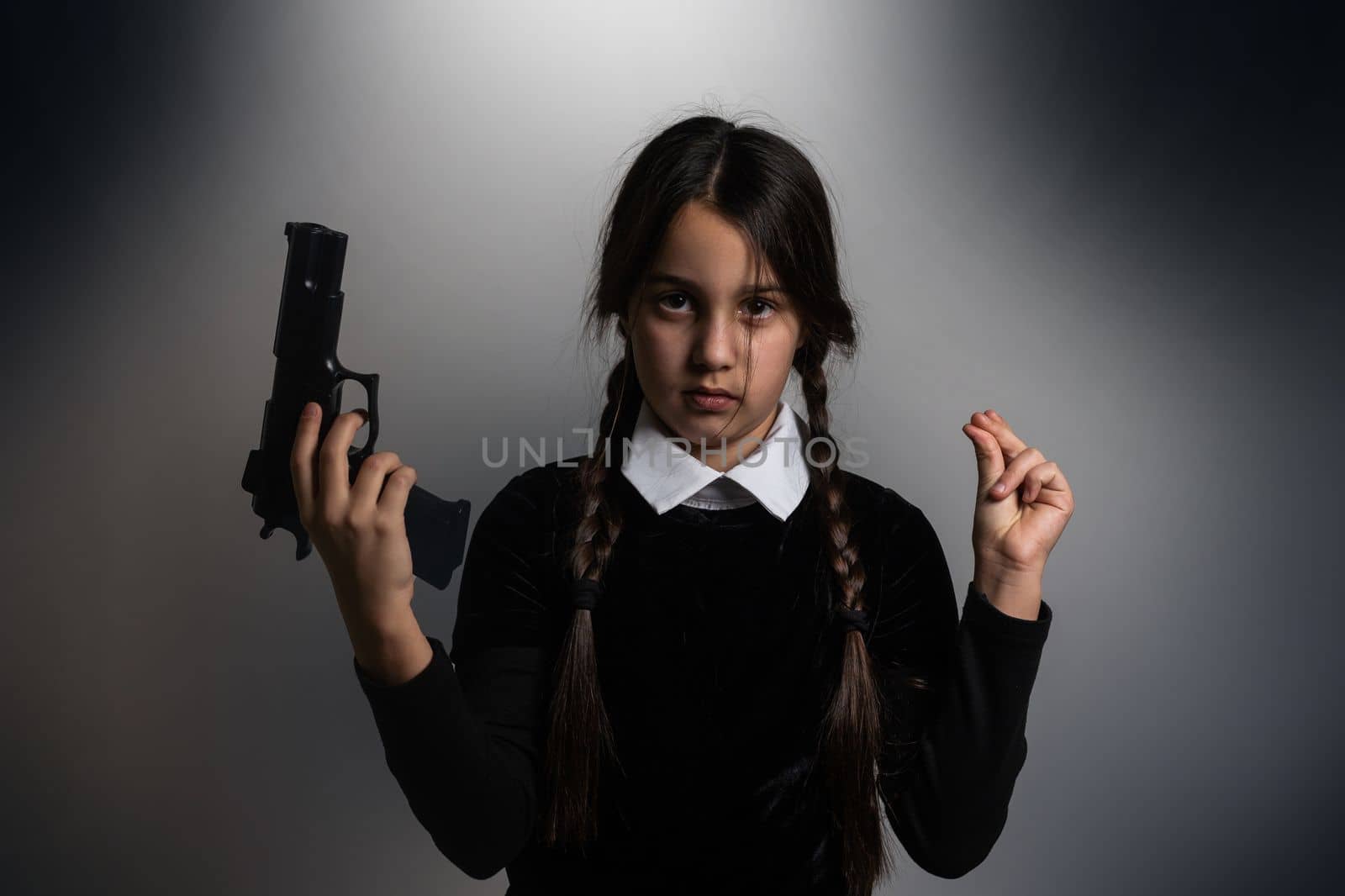 A girl with braids in a gothic style on a dark background with weapons.