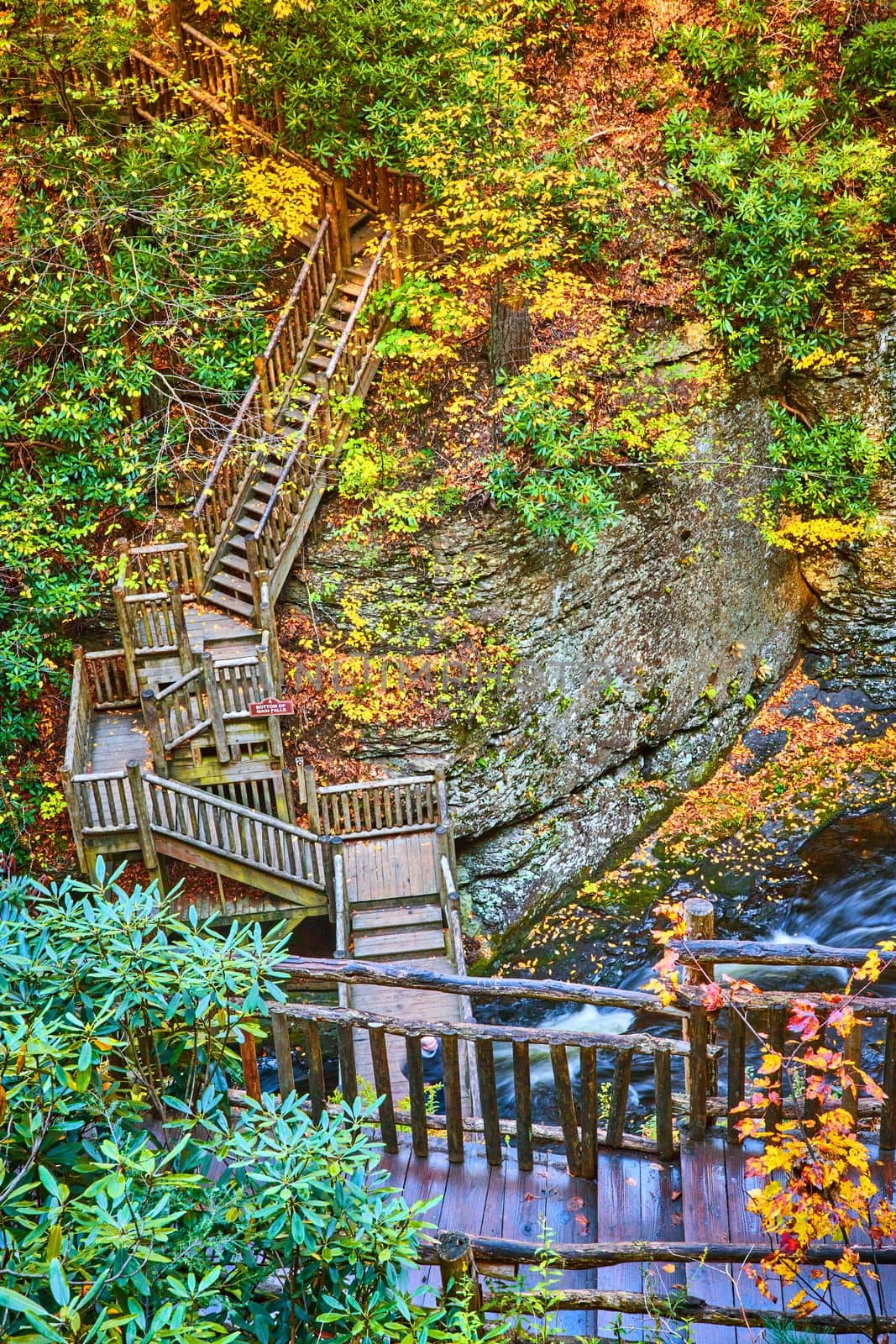 Image of Endless boardwalk stairs across river and up cliffs surrounded by fall foliage