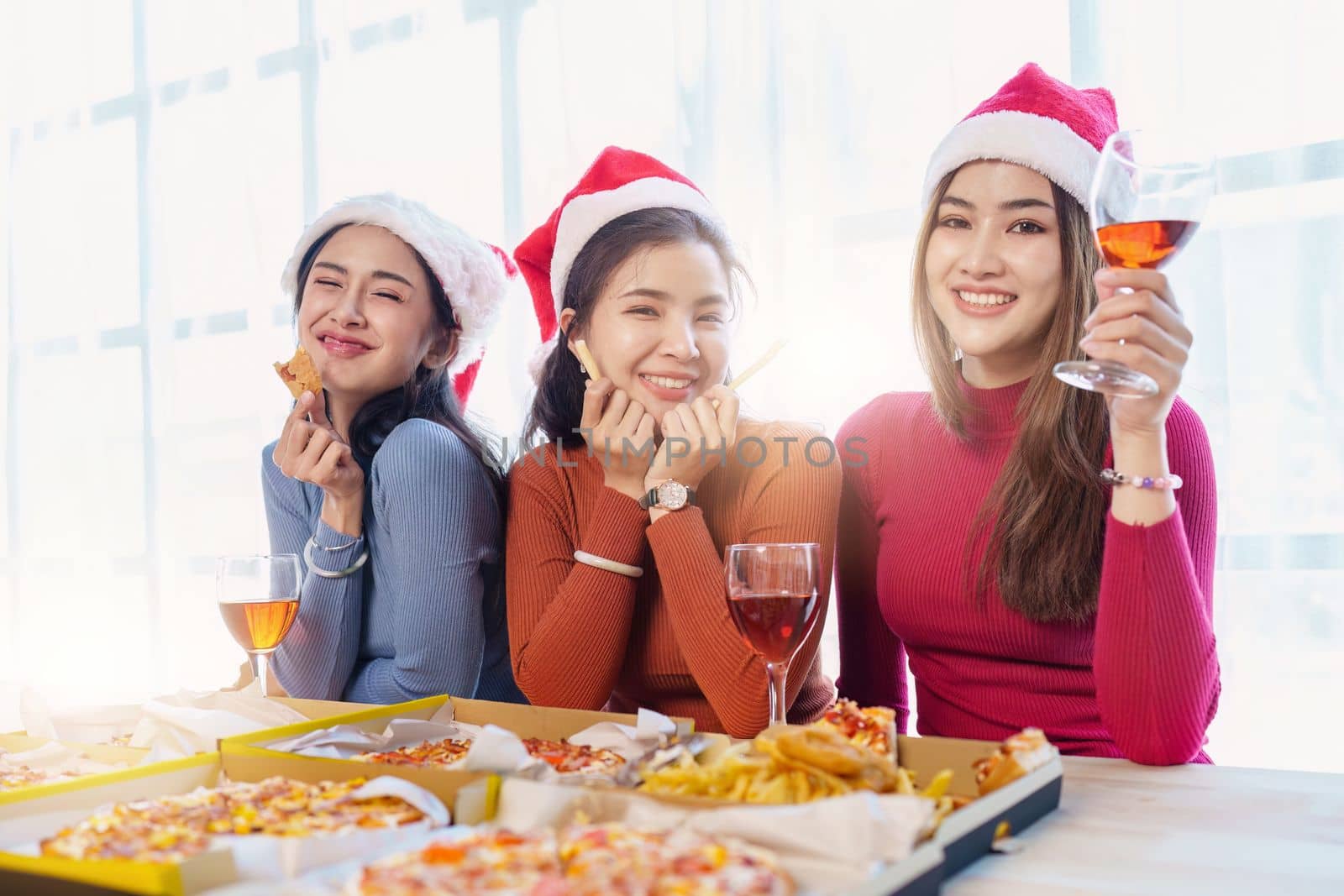 Friends at birthday party clinking glasses with champagne and pizza, enjoying Christmas vacation, pizza on the table. Holiday Party event.