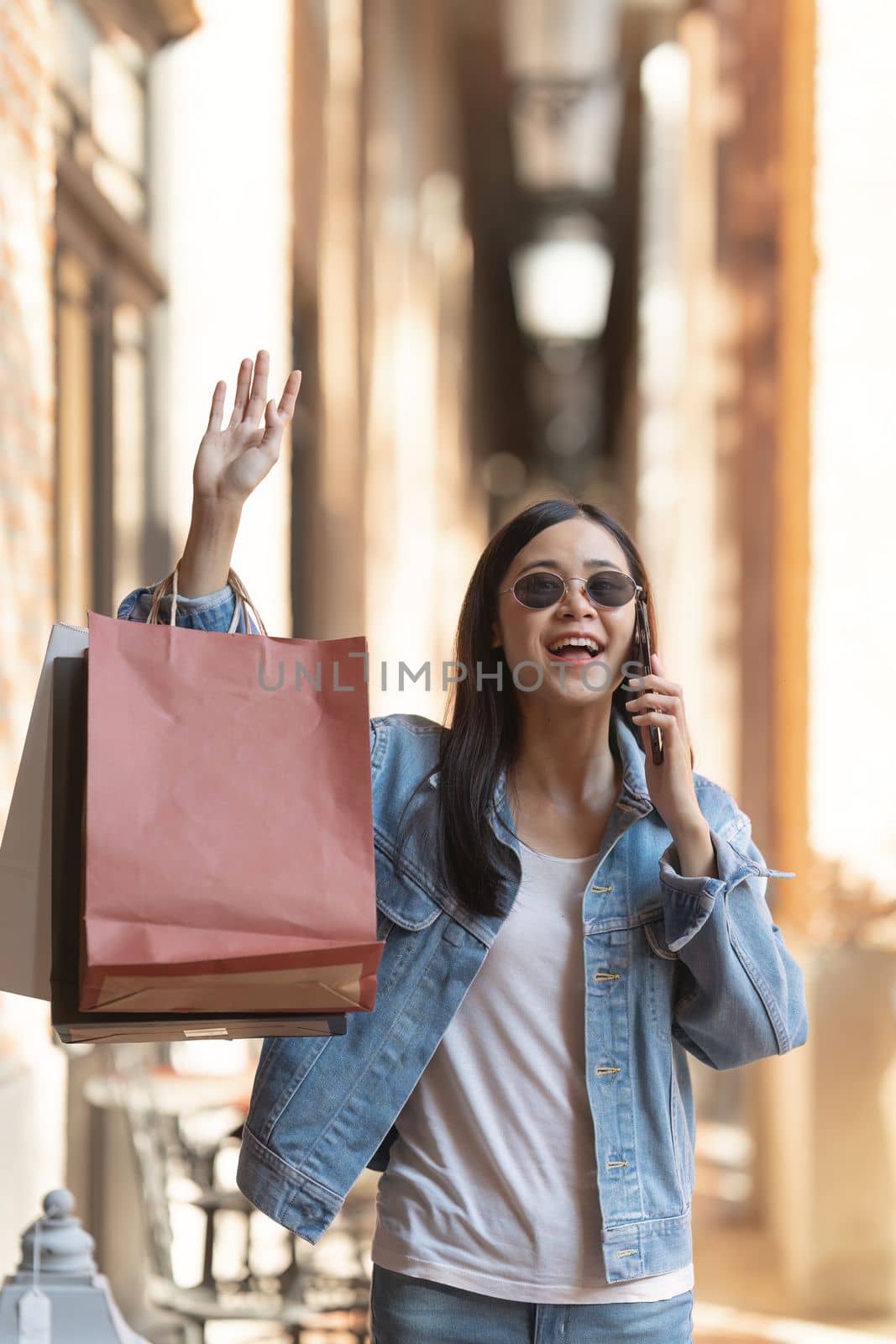 Asian fashionable woman walking at shopping mall with shopping bags while flash sale promotion.