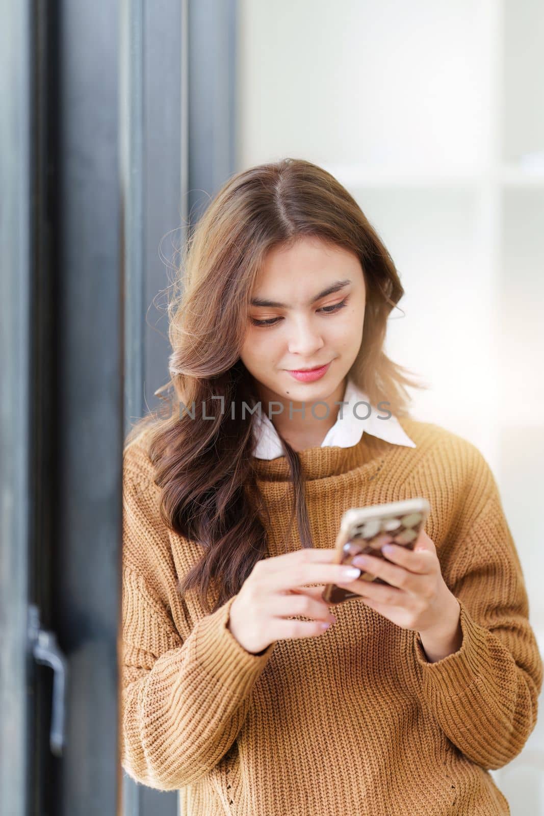 Young Asian Woman using smart phone at home. Female holding cellphone checking email or social media on internet.