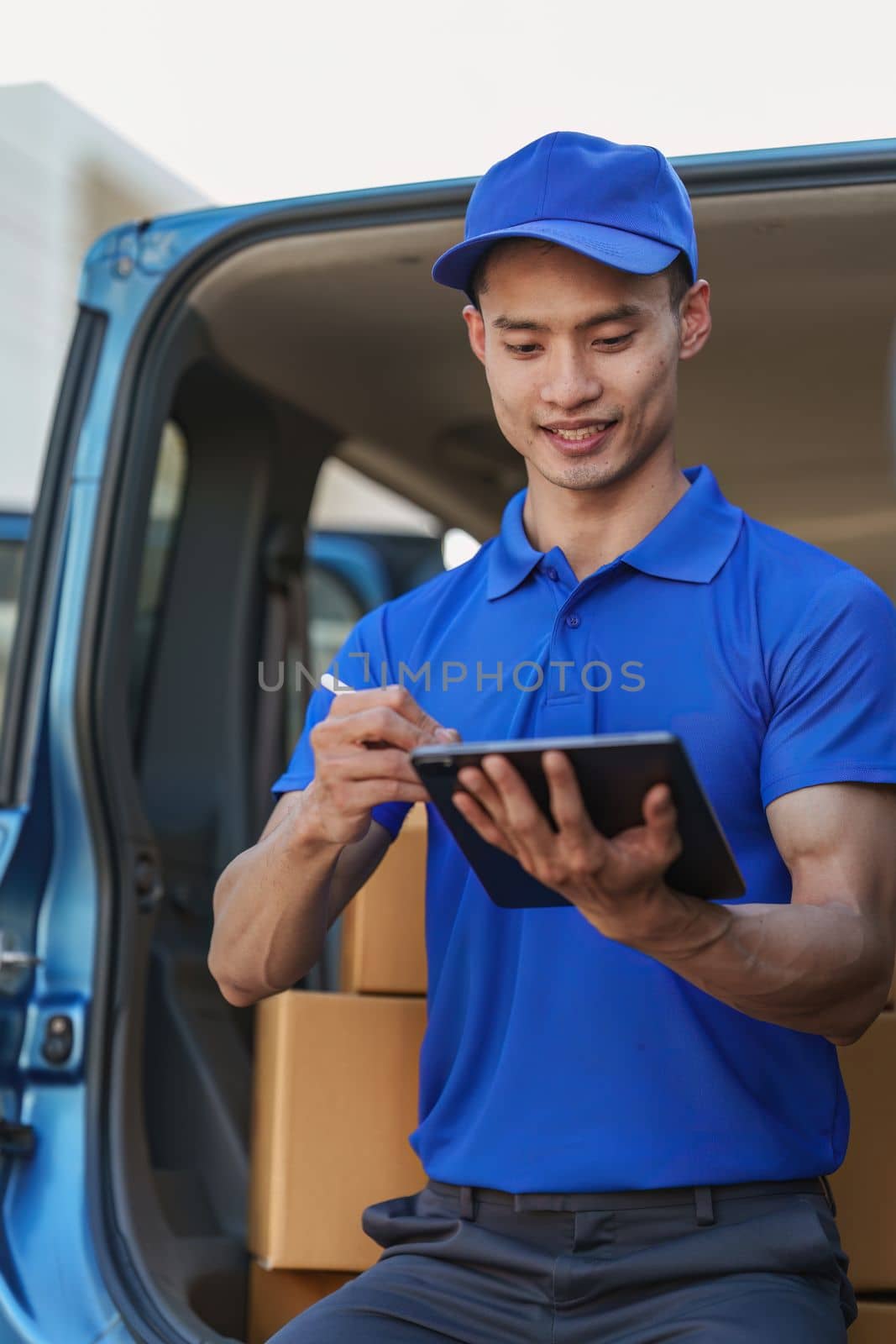 Asian courier with parcel and delivery logistic concept. Delivery man using digital tablet by itchaznong