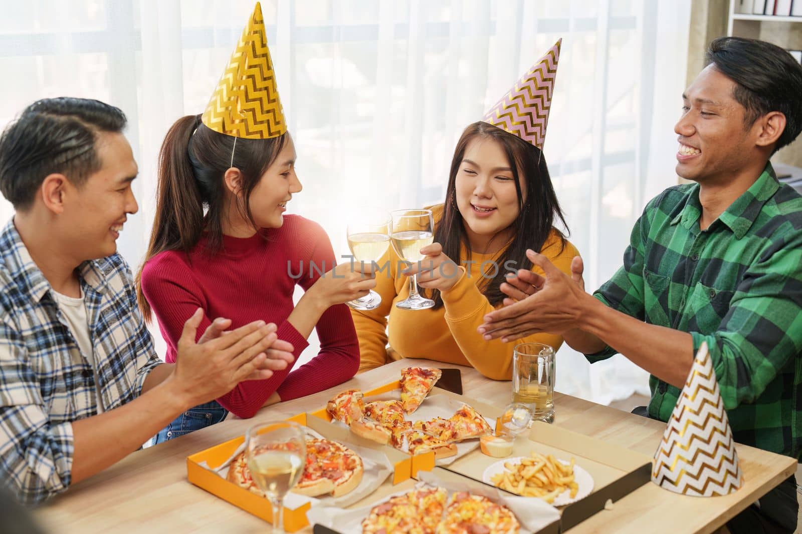 Friends at birthday party clinking glasses with champagne and pizza, enjoying Christmas vacation, pizza on the table. Holiday Party event