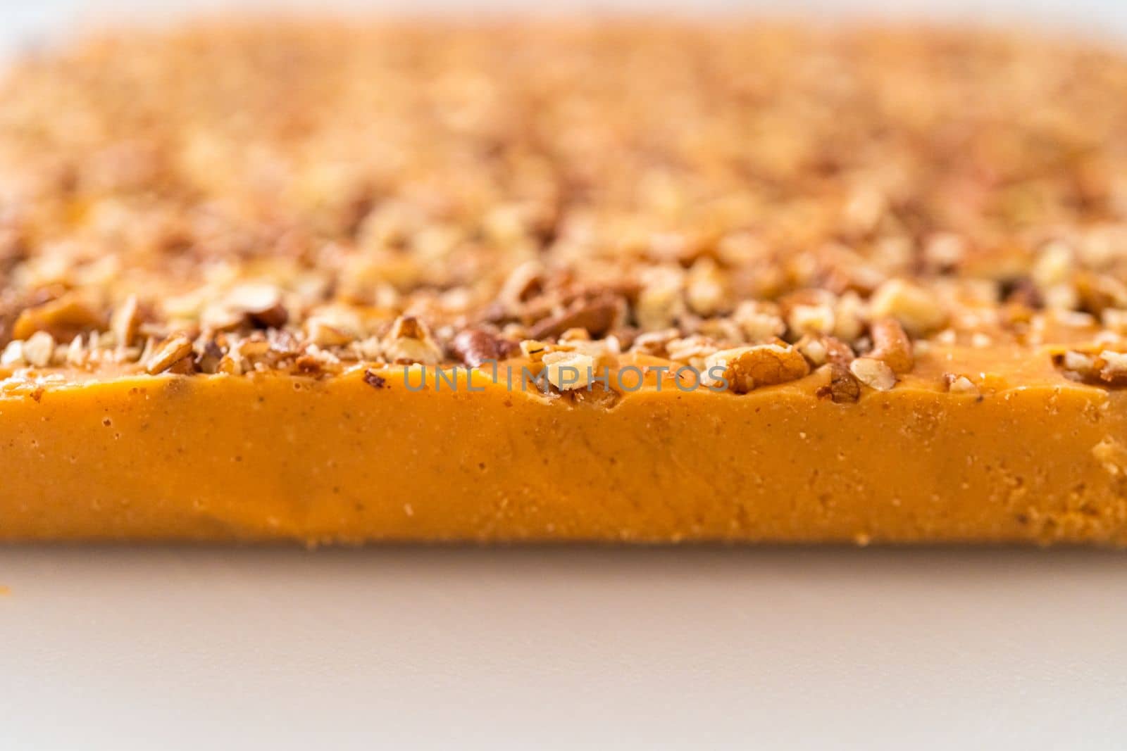 Scoring pumpkin spice fudge using a wheel dough cutter for cutting into small pieces.