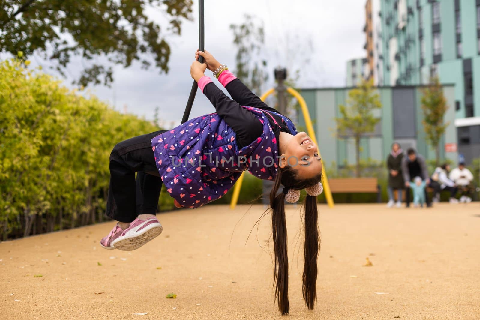 Smiling little girl swinging on a rope at a playground.