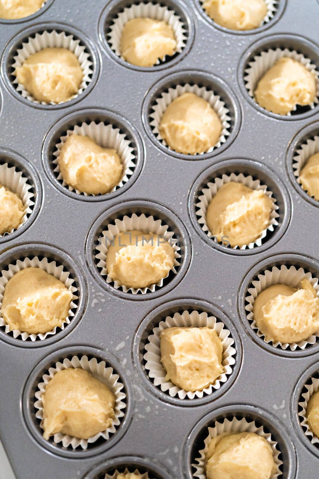 Scooping cupcake batter with dough scoop into a baking pan with liners to bake American flag mini cupcakes.