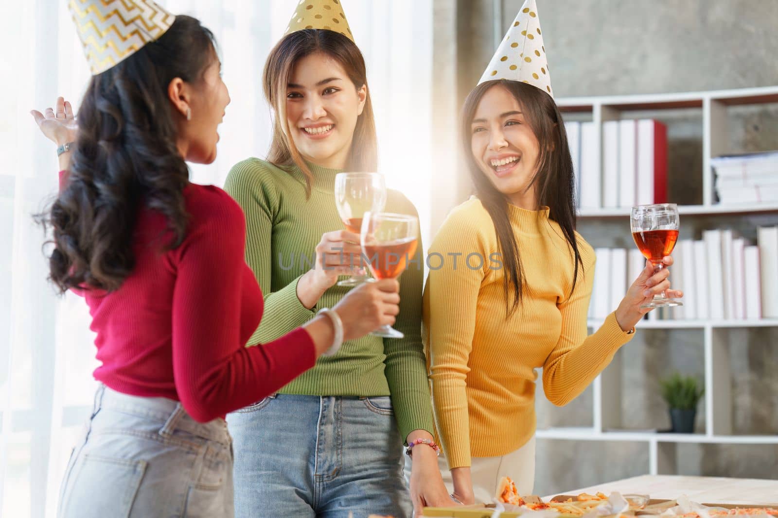 Friends at birthday party clinking glasses with champagne and pizza, enjoying christmas vacation, pizza on the table. Holiday Party event.