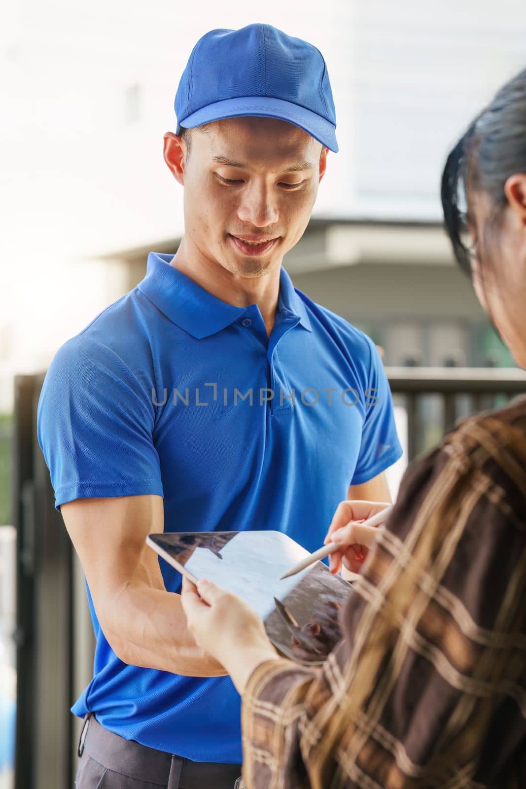 Asian courier with parcel and delivery logistic concept. Delivery man carrying package while customer sign in tablet. by itchaznong